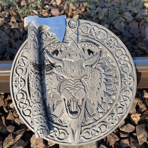 May include: A silver axe with a carved wooden handle and a wolf head design on a round, silver plaque with a Celtic knot border.