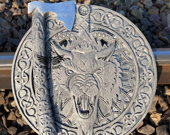 May include: A silver axe with a carved wooden handle and a wolf head design on a round, silver plaque with a Celtic knot border.
