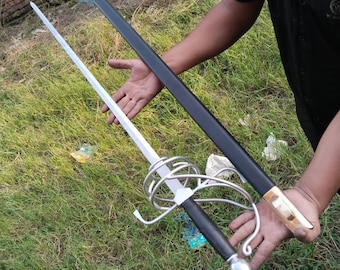 May include: Two swords, one with a black scabbard and one with a silver blade and a decorative guard. The swords are held by a person's hands.