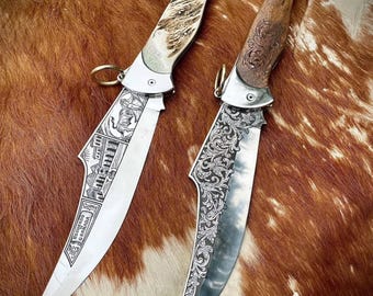 May include: Two ornate, silver folding knives with intricate engravings. One knife has a brown wooden handle and the other has a bone handle. Both knives have a curved blade.