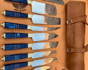 May include: Set of nine blue and gold handled knives with a leather carrying case. The case has the text "The Casa Collection" printed on it. The knives have a silver blade and a blue and gold handle with a decorative design. The knives are arranged in a row with the handles facing up. The case is closed and has a strap with a buckle.