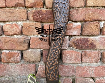 May include: A hand-crafted axe with a wooden handle carved in the shape of a raven. The handle is decorated with a Celtic knot design. The axe head is made of steel and features a raven design.
