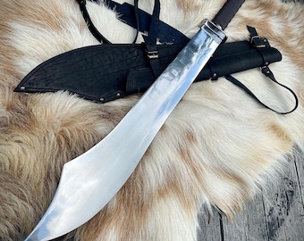 May include: A silver sword with a curved blade and a black leather scabbard with a strap. The sword is lying on a white and brown fur rug.