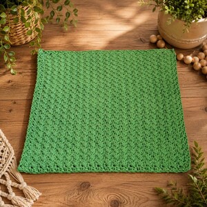 May include: A square, bright green crochet washcloth featuring a consistent, textured stitch pattern. The textile is crafted with a repeating, dense weave that creates a uniform surface across the entire piece, showcasing a vibrant, solid color.