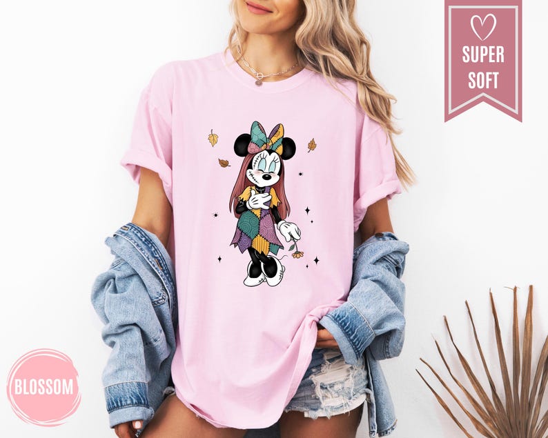 Puede incluir: Camiseta rosa claro con un gr&aacute;fico de Minnie Mouse con un disfraz de patchwork. El dise&ntilde;o incluye un lazo colorido, hojas de oto&ntilde;o y el texto "Blossom" en un c&iacute;rculo rosa. La camiseta tiene una etiqueta "Super Soft".
