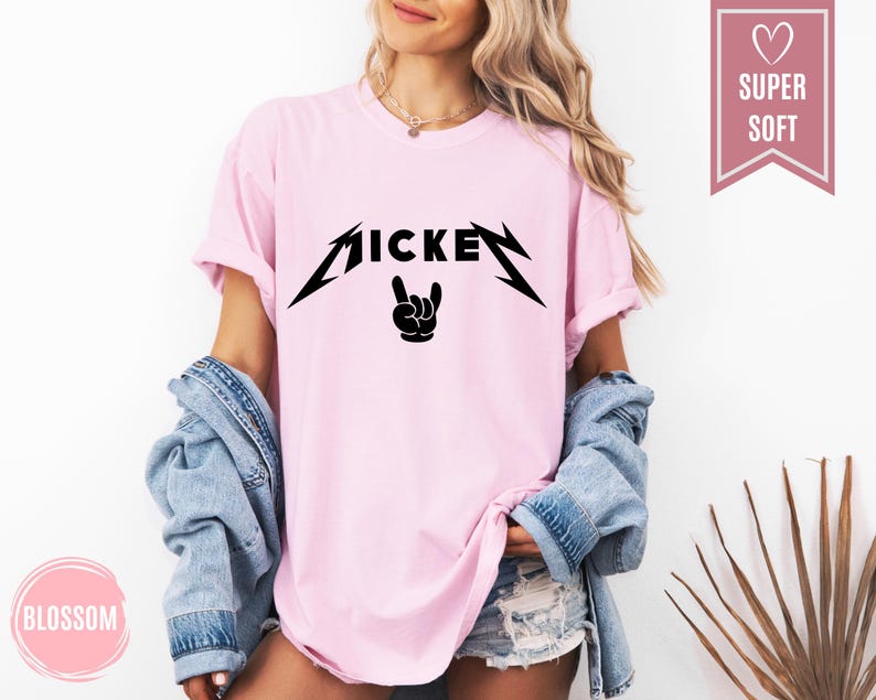 Pu&ograve; includere: T-shirt rosa chiaro con la scritta "MICKEY" in nero, con un carattere stilizzato e un gesto della mano rock and roll sotto. La maglietta ha maniche corte e una vestibilit&agrave; ampia.