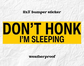 May include: A yellow 11x3 inch bumper sticker with the text "DON'T HONK I'M SLEEPING" in black. The word "weatherproof" is below the text. The background is white.