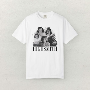 May include: White t-shirt featuring a black and white graphic of several people and the name "HIGHSMITH" in a bold, black font. The shirt has a classic crew neck and short sleeves, suitable for casual wear.