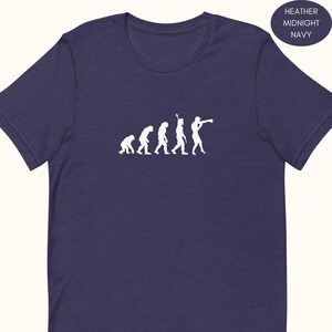 May include: Heather midnight navy t-shirt featuring a white graphic of human evolution ending with a boxer. The shirt has a crew neck and short sleeves. The text "Heather Midnight Navy" is in a circle on the upper right.