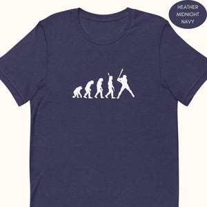 Può includere: T-shirt blu navy con grafica bianca raffigurante l'evoluzione del baseball. Il design mostra una serie di figure che si trasformano in un giocatore di baseball. Il colore della maglietta è blu scuro.