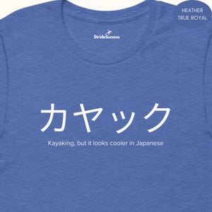 May include: A blue heather t-shirt with the Japanese word for kayaking, "カヤック", written in white. The text "Kayaking, but it looks cooler in Japanese" is written below the Japanese word.