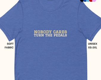 Könnte beinhalten: Ein königsblaues T-Shirt mit dem Text "NOBODY CARES TURN THE PEDALS" in Gelb. Das Shirt ist aus weichem Stoff und in verschiedenen Farben erhältlich.