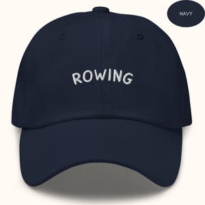 May include: A navy blue baseball cap with white embroidered text that says "ROWING".