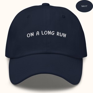 May include: A navy blue baseball cap with white embroidered text that reads "ON A LONG RUN".