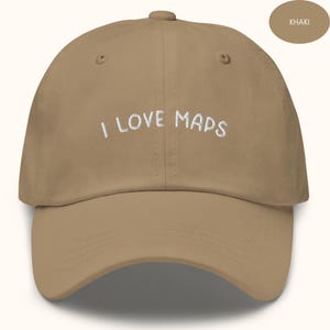 Könnte beinhalten: Khaki-farbene Baseballkappe mit dem gestickten Text "I LOVE MAPS" in Weiß. Die Kappe hat einen gebogenen Schirm und eine runde Krone. Das Wort "KHAKI" wird in einem kleinen Oval oben rechts angezeigt.