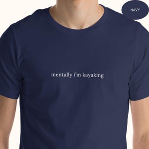 Op de afbeelding: Marineblauw T-shirt met de witte tekst "mentally I'm kayaking". Het shirt heeft een ronde hals en is effen van kleur. De tekst is gecentreerd op de borst.
