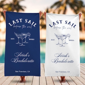 May include: Two white beach towels with blue text and a graphic of three martini glasses. The text reads "Last Sail Before the Veil" with the year 2025 and the words "Sarah's Bachelorette" and "San Francisco, CA".