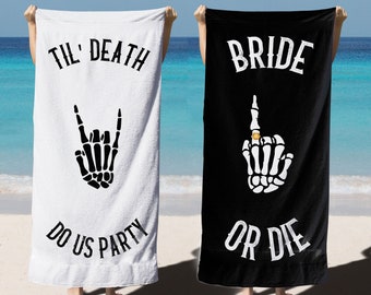 May include: Two white beach towels with black text and skeleton hand graphics. One towel says "Til' Death Do Us Party" with a skeleton hand making a rock and roll sign. The other towel says "Bride Or Die" with a skeleton hand making a middle finger gesture with a ring on the finger.
