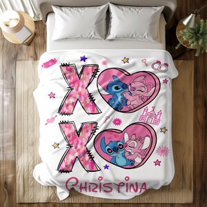 May include: White fleece blanket with pink hearts and a pink and blue cartoon couple. The blanket has the letters XOXO and the name Christina printed on it.