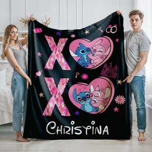 May include: Black fleece blanket with a pink and blue cartoon couple, a pink heart with the letters XOXO, and the name Christina.