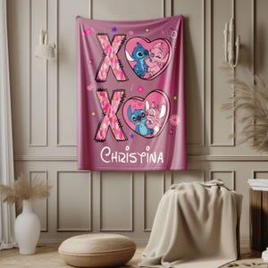May include: Pink and blue throw blanket with a pink and white heart design featuring Stitch and Angel from Lilo & Stitch. The blanket has the letters XO and the name Christina.