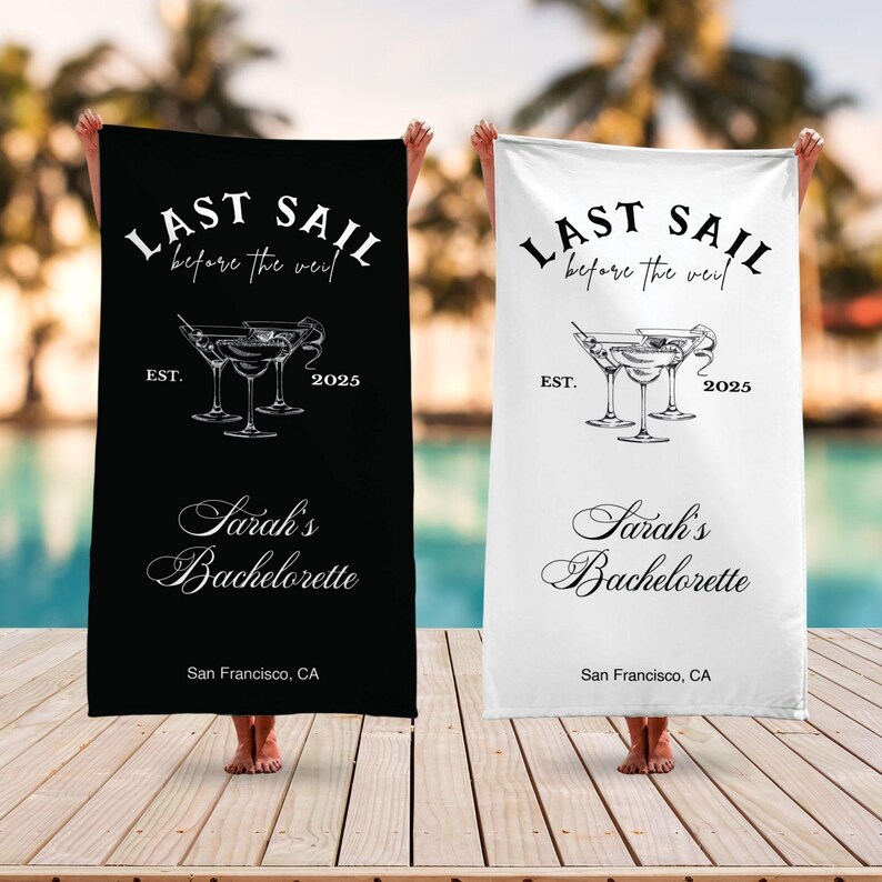 May include: Two black and white beach towels with the text "Last Sail Before the Veil" and "Sarah's Bachelorette" with a graphic of three martini glasses. The towels are on a wooden deck.
