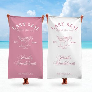 May include: Two pink and white beach towels with the text "Last Sail Before the Veil" and "Sarah's Bachelorette" printed on them. The towels also feature a graphic of three martini glasses.