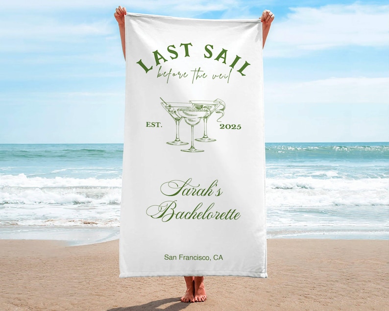 May include: White beach towel with green text that reads "Last Sail Before the Veil" and "Sarah's Bachelorette" with a drawing of three martini glasses. The text also includes "Est. 2025" and "San Francisco, CA".