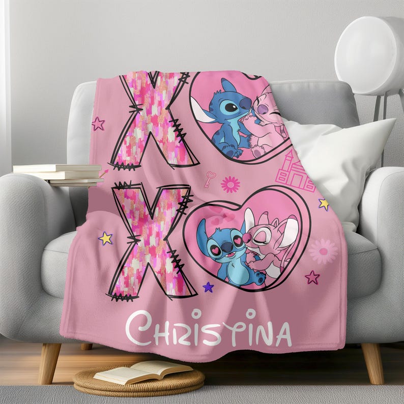 May include: Pink fleece throw blanket with a pink and white X and O design. The blanket features a cartoon image of Stitch and Angel from the Disney movie Lilo & Stitch. The blanket is personalized with the name "Christina".