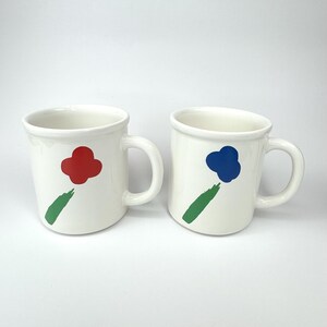 Pode incluir: Duas canecas de cer&acirc;mica branca com desenhos abstratos de flores verdes, vermelhas e azuis.