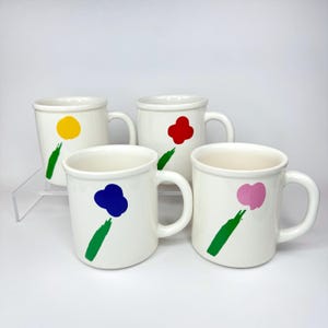 May include: Set of four white ceramic mugs with green, yellow, red, and blue abstract flower designs.