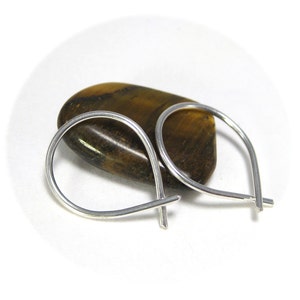 May include: A pair of silver teardrop shaped hoop earrings. The earrings are made of thin wire and are simple and elegant.