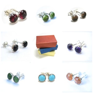 May include: Assortment of gemstone stud earrings in various colors, including red, green, black, purple, blue, and orange. The earrings are displayed on a white background.