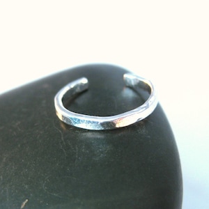 May include: A silver toe ring with a hammered finish. The ring is simple and elegant, and would make a great gift for a friend or loved one.
