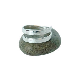 May include: Two silver hammered rings stacked on top of each other, resting on a gray rock.