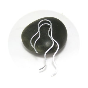 May include: A pair of silver wavy wire earrings. The earrings are long and thin, with a slight curve at the top.