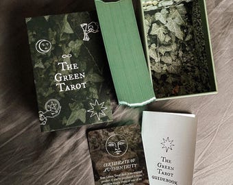 May include: A green tarot deck with a certificate of authenticity and a guidebook. The deck features a green and black design with ivy and a white infinity symbol. The guidebook is white with a green star and the text "The Green Tarot Guidebook by Lida Parlova".
