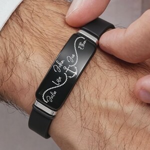 May include: Black bracelet with a rectangular, engraved plate featuring names and an anchor design. The bracelet is made of black leather and silver-toned metal accents. The names "Julia", "Lisa", "John", "Joe", and "Ethan" are visible.