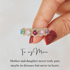 May include: A gold-toned ring featuring five round-cut multi-colored gemstones, including blue, white, red, pink, and purple, surrounded by small clear stones. Text reads: To my Mom. Mother and daughter never truly part, maybe in distance but never in heart.