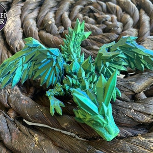May include: A green, 3D printed dragon figurine with a spiky, crystalline design. The dragon has wings and a long tail. The figurine is made of a shiny, iridescent material.