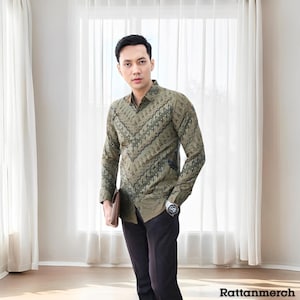 May include: A green and black patterned long-sleeve shirt with a button-down collar. The shirt has a geometric pattern and is worn by a person with a watch on their wrist.