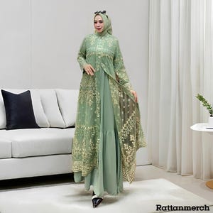 May include: A sage green dress ensemble featuring a long-sleeved dress with a tiered skirt, overlaid with a matching open-front jacket. The jacket and dress are adorned with gold embroidery. The outfit is worn with a matching head covering.