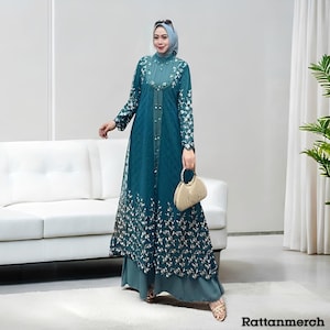 Puede incluir: Vestido formal de color turquesa con mangas largas y bordados florales. El vestido presenta una parte delantera abotonada y una falda en capas. Un pañuelo a juego y un bolso dorado completan el conjunto. El texto "Rattanmerch" es visible.