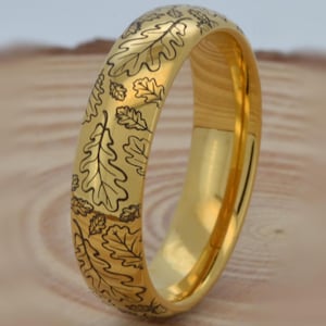 May include: A gold wedding band with an engraved oak leaf design.