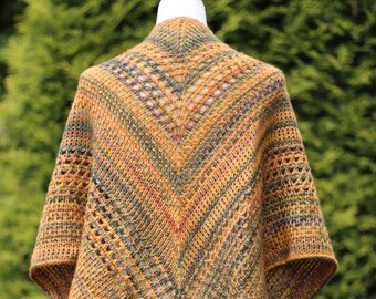 Puede incluir: Un chal triangular tejido en un hilo multicolor con una mezcla de tonos marrones, verdes y naranjas. El chal tiene un patrón de encaje y se muestra en un maniquí blanco.