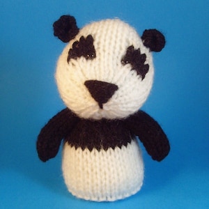 May include: A white and black knitted panda bear toy with black eyes and a black nose.