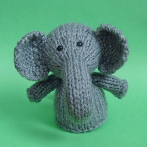 Può includere: Un giocattolo di elefante di lana grigia con occhi neri. L'elefante ha una lunga proboscide e grandi orecchie.