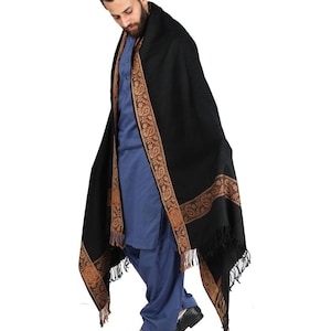 May include: A black shawl with a gold and brown paisley border. The shawl is draped over a person's shoulders and is worn with a blue shirt.