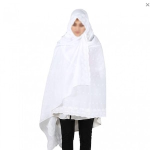 May include: White prayer shawl with lace trim and small white dots. The shawl is draped over a person's shoulders and head.