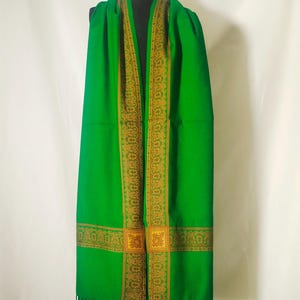 May include: A green shawl with a gold embroidered border. The shawl has a fringe on the bottom.